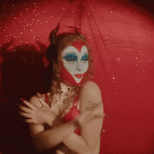 a woman with horns painted on her face and a heart on her face