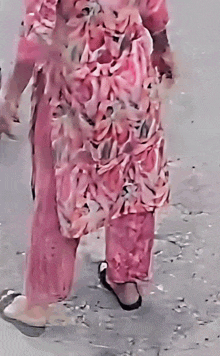 a woman in a pink floral dress is walking on the street