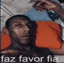 a man is laying on a bed with an orange pillow and the words faz favor fia above him .