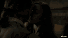 a man and woman are kissing in front of a window in a dark room .
