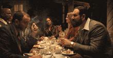 a group of people are sitting around a table with plates of food
