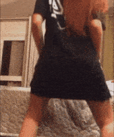 a woman wearing a black shirt with the letter a on it is dancing on a bed .