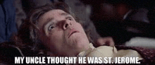 a man is laying on a bed with his head on a blanket and a man is touching his neck .