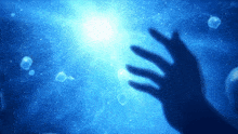 a silhouette of a hand reaching out towards a bright light