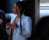 a woman with dreadlocks is wearing a plaid jacket and a sweater .