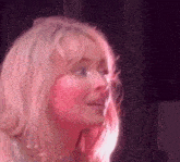 a close up of a woman 's face with a pink light behind her