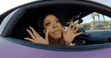 a woman sitting in a purple car with her hands up