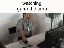 a man is sitting at a desk using a computer mouse and the words watching garand thumb are above him