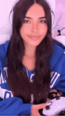 a woman wearing headphones and a blue hoodie is holding a controller