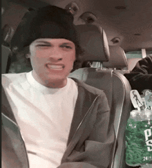 a man is sitting in a car next to a bottle of ts