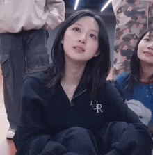 a girl wearing a black sweatshirt with the letter r on the front