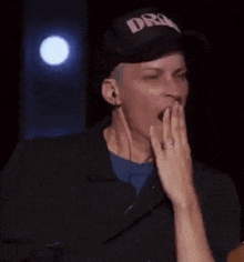 a man wearing a hat is yawning while wearing headphones and a ring on his finger .