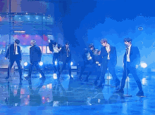 a group of men are dancing on a stage in front of a colorful background .