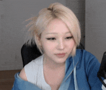 a woman with blonde hair is wearing a blue hoodie