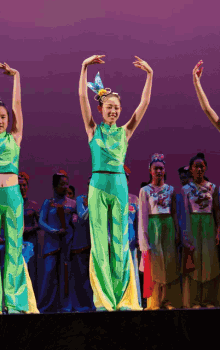 a group of women are dancing on a stage and one of them has a flower in her hair