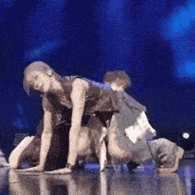 a group of people are dancing on a stage and one of them is kneeling down