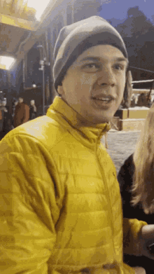 a young man wearing a yellow jacket and a beanie