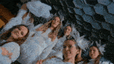 a group of women are posing for a picture in white dresses