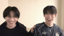 two young men are standing next to each other in a room and smiling .