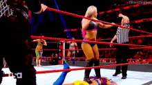 a group of women are wrestling in a ring while a referee looks on .