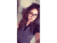 a woman wearing glasses and a vest is taking a picture of herself