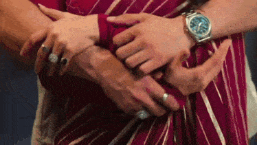 a man and a woman are hugging each other and the woman is wearing a watch .