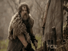 a man in a fur coat is kneeling down in a field .