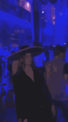a woman wearing a sombrero stands in a crowded room
