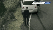 a man standing on the side of a road next to a car with the license plate number 58
