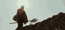 a man holding a trident on top of a dirt hill with nandamurifans.com written on the bottom