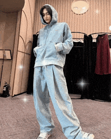 a person wearing a hoodie and jeans stands in front of a fire extinguisher