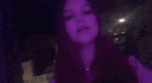 a woman with red hair is taking a selfie in a dark room with purple lights .