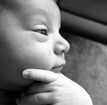 a close up of a baby 's face with a hand on its chin