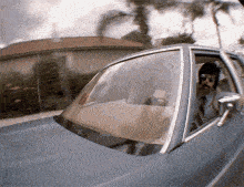 a man is driving a blue car with his door open