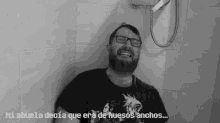 a man with a beard and glasses is standing in a shower with a shower head .