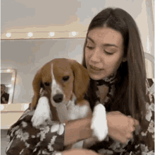 a woman is holding a beagle dog in her arms .