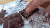 a person is taking a piece of chocolate out of a foil wrapper