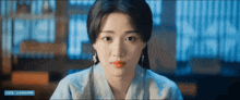 a close up of a woman 's face with a blue banner behind her that says ' chinese '