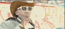 a man wearing sunglasses and a cowboy hat is smoking a cigar