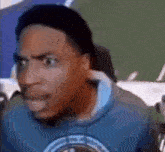a man in a blue sweatshirt is making a funny face in a blurry photo .