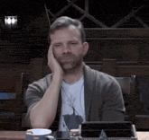 a man sitting at a table with his hand on his head