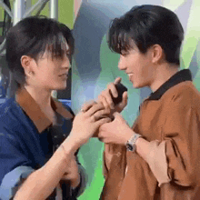 two young men are holding hands and looking at each other while standing next to each other .