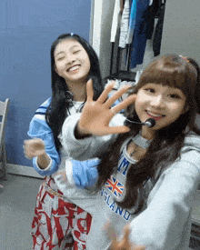 two girls are posing for a picture and one has a sweatshirt that says england on it