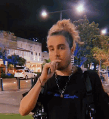 a man wearing a black shirt with the word iot on it is smoking an electronic cigarette