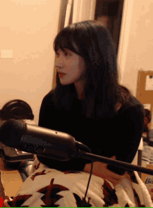 a woman sitting in front of a microphone with a box in the background that says bis