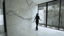 a woman is standing in a room with a large window and the words made in animatica on the bottom right