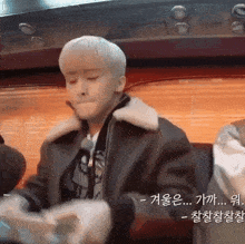 a man with white hair is sitting in a chair with korean writing on the bottom of the screen
