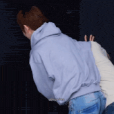 a man in a blue hoodie is hugging another man in a white sweater with dohun fon written on the bottom right