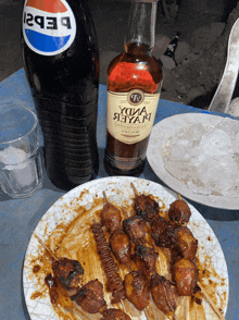a plate of food next to a pepsi bottle and a bottle of alcohol
