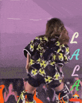 a woman is dancing in front of a crowd with the letters l and a on the bottom